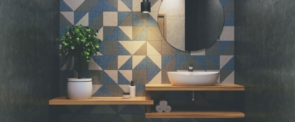 banyoda antrasit indigo mavi ve krem renklerde geometrik formlar iceren duvar seramigi kullanimi, ahsap acik raflar ve tezgah ustu lavabo