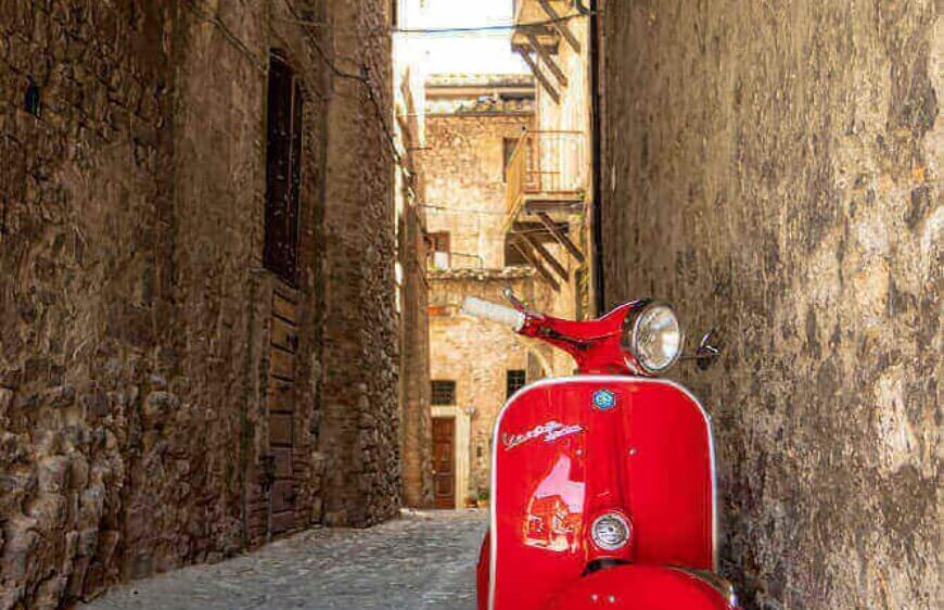 roma italyada eski kasaba yoluna park etmis kirmizi vespa motor