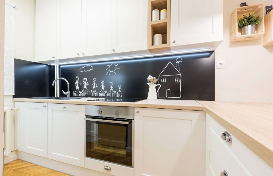 acik renk mutfak dolaplari ve ahsap tezgah kullanilan mutfak tasariminda tezgah arasi kara tahta uygulamasi