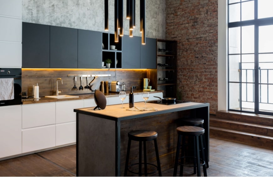 koyu tonlarin hakim oldugu modern mutfak stilinde, ahsap tezgah, beyaz mutfak dolaplari, tugla ve gri duvar, siyah ust dolaplar ile sakin tonlarin ve duz geometrik desenlerin kullanimi