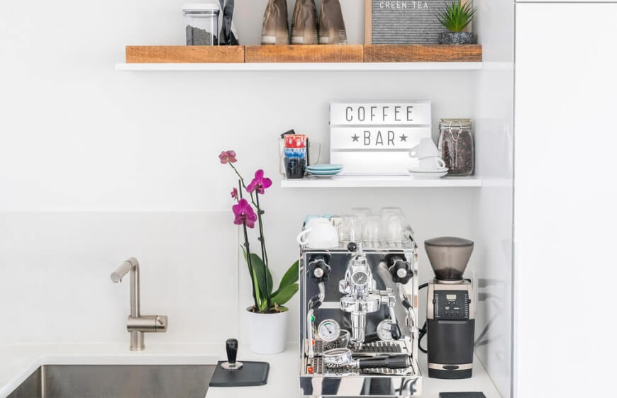 luks modern beyaz minimal mutfak tezgahinda profesyonel barista espresso makinesi ve ahsap acik kahve rafi