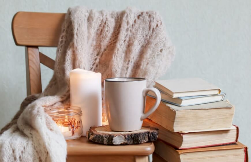 ahsap sandalye uzerinde orgu cozy battaniye mum sicak kahve ve kitaplar ile okuma kosesi