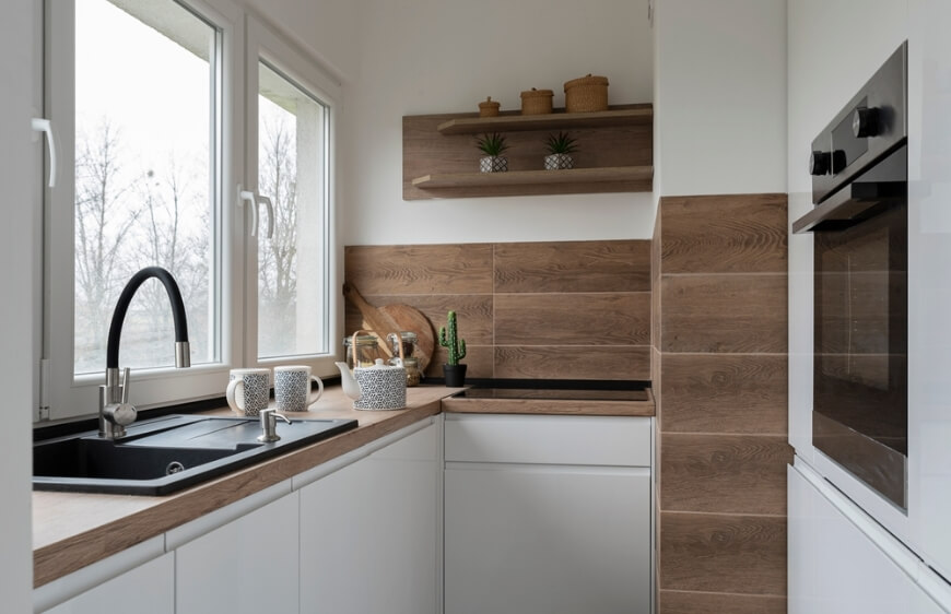 kucuk mutfak beyaz modern mutfak mobilyalari, duvarda ahsap gorunumlu seramik, pencere yani mutfak lavabosu ve bataryasi