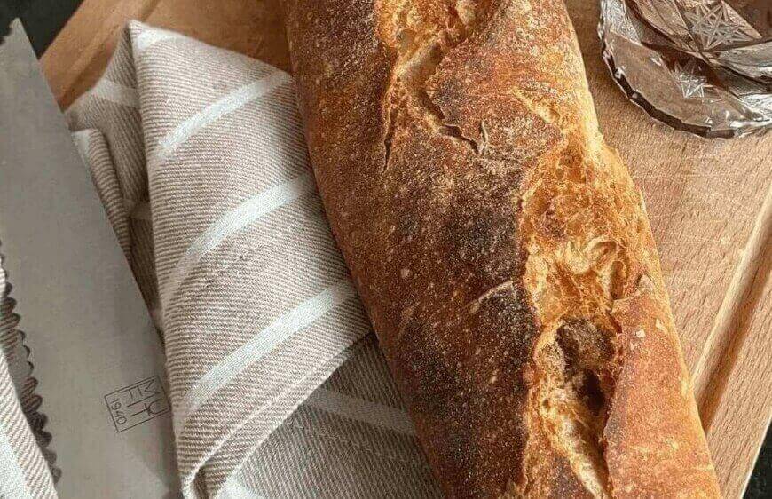 beyaz bej cizgili keten pecete ve ahsap kesme tahtasi uzerinde somun baget ekmek 