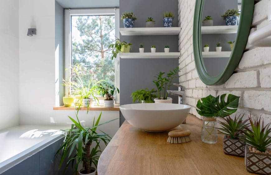 ahsap banyo tezgahi uzerinde canak lavabo ve canli bitkiler banyoya dogal bir hava kazandirir