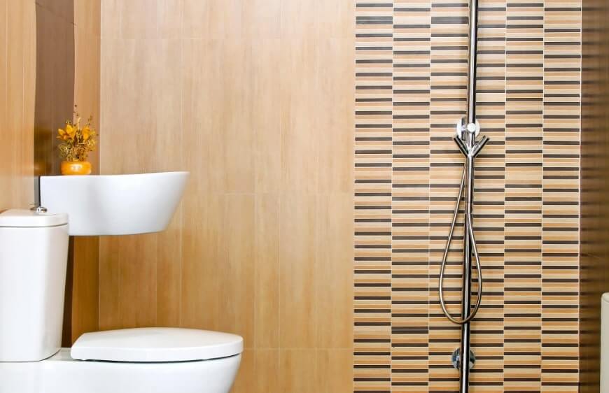 asma lavabo ve yerden klozet olan banyoda ahsap gorunumlu farkli boyutlarda dosenen duvar karosu