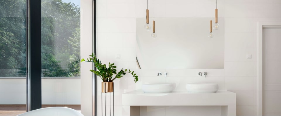 ikiz lavabolu, ankastre krom armaturlu, sarkit lambali, yesil canli bitkili ve yerden tavana kadar pencereli minimalist banyo