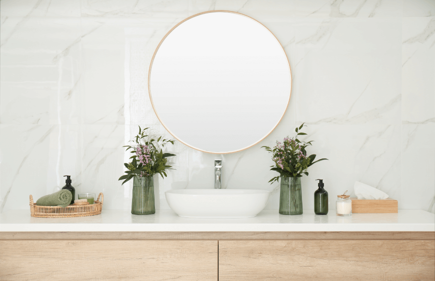 ahsap banyo dolabi uzerinde canak kare lavabo yuvarlak ayna, lavabo yani yesil vazo ve bitkiler