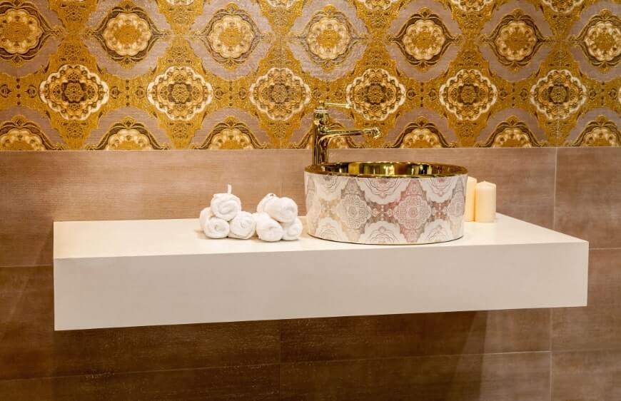klasik stil banyoda gold altin detayli duvar karosu ve lavabo haznesi ve pirinc armatur